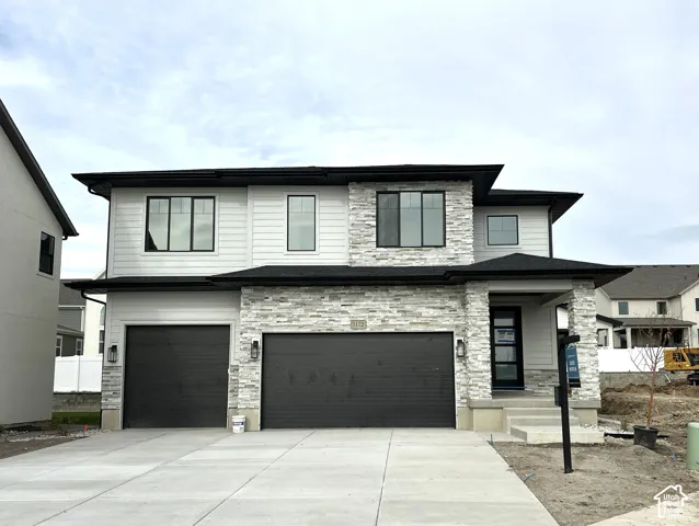 Two-story exterior featuring horizontal siding, natural stone veneer accents, multi-car garage with black paneling, and a covered front porch entry