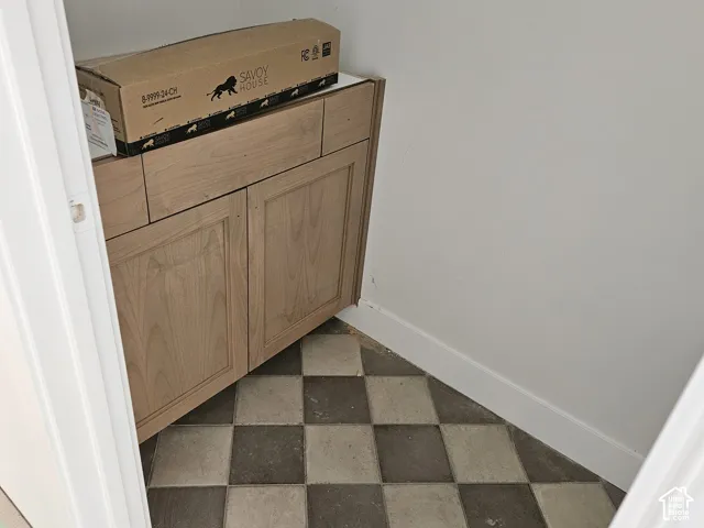 Corner wood-finish cabinetry with multiple doors and drawers, set against a checkered floor with light and dark tiles
