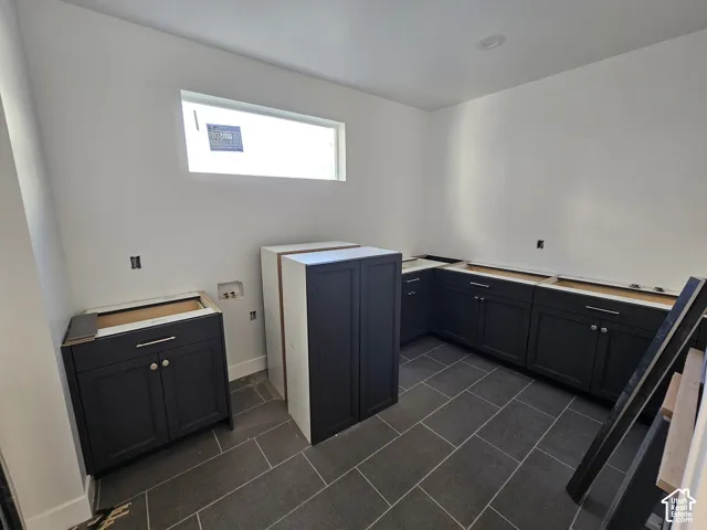 Dark cabinetry with silver-tone hardware, rectangular window, recessed lighting, and dark tile flooring