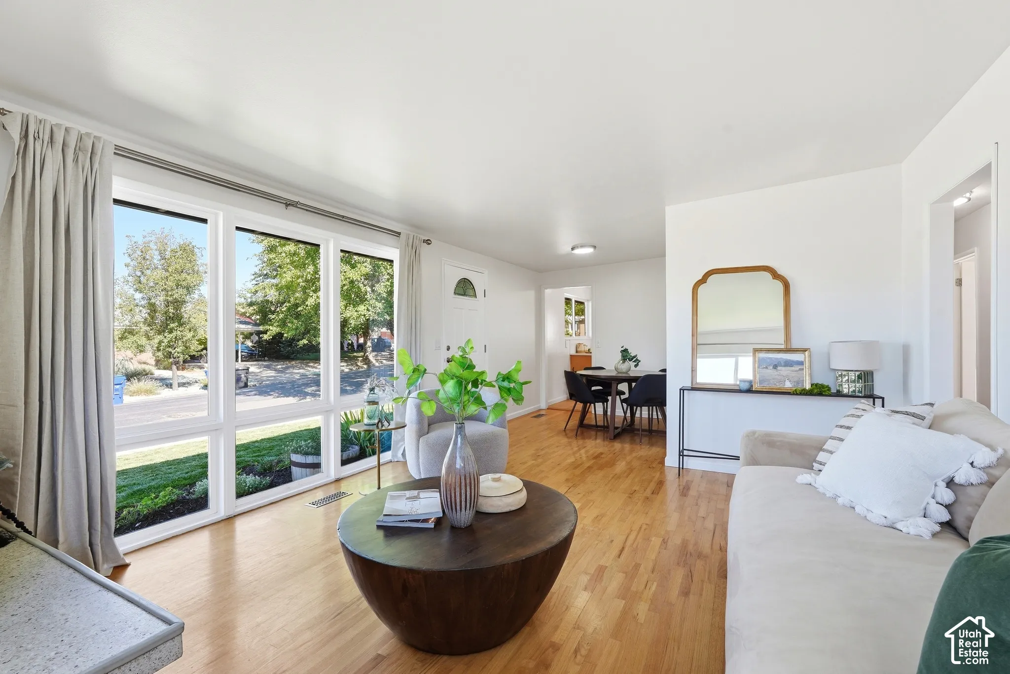 Bright living space featuring large picture windows, wood-finish flooring, and crisp white walls