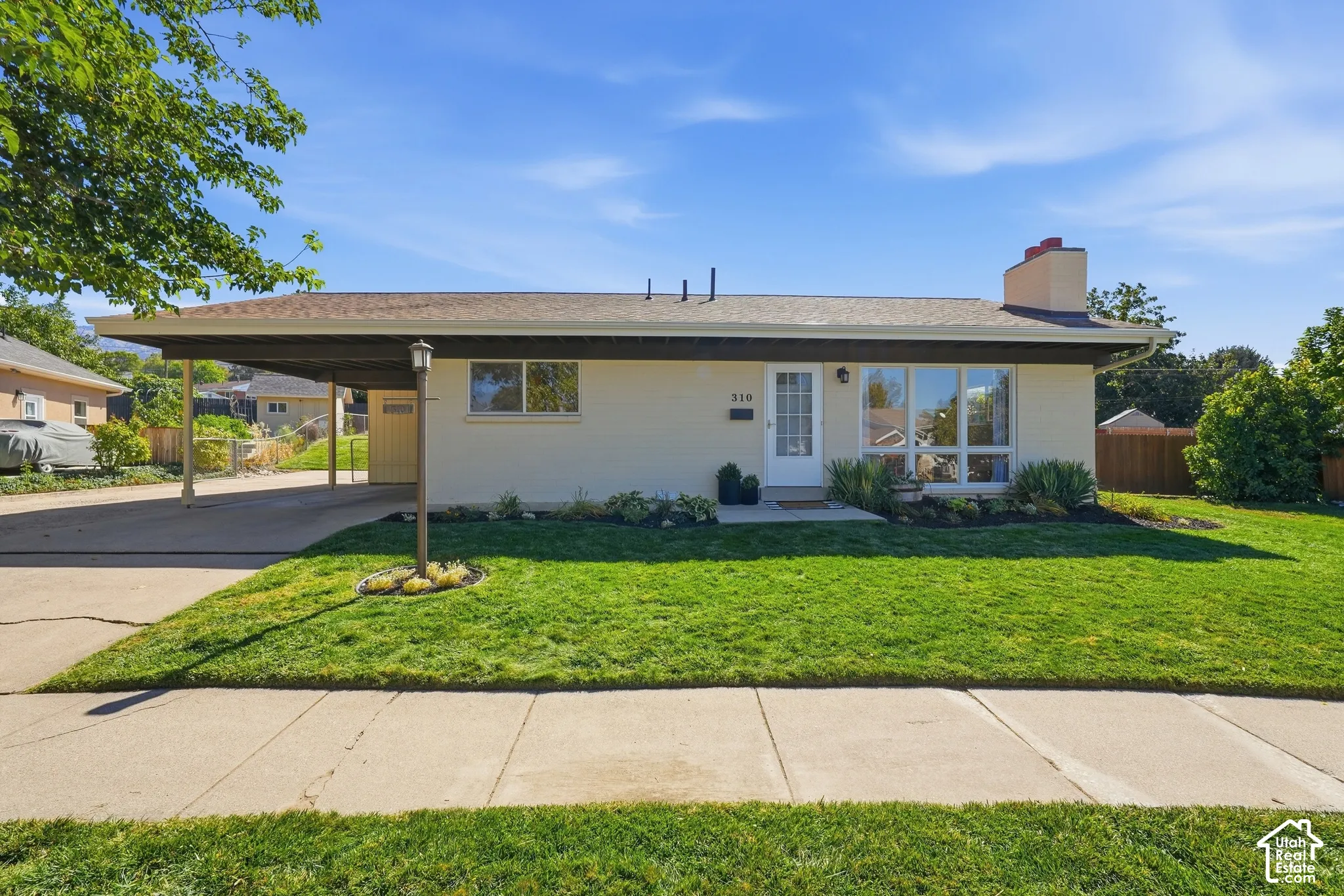Single-story residence featuring a carport, front lawn, and established landscaping