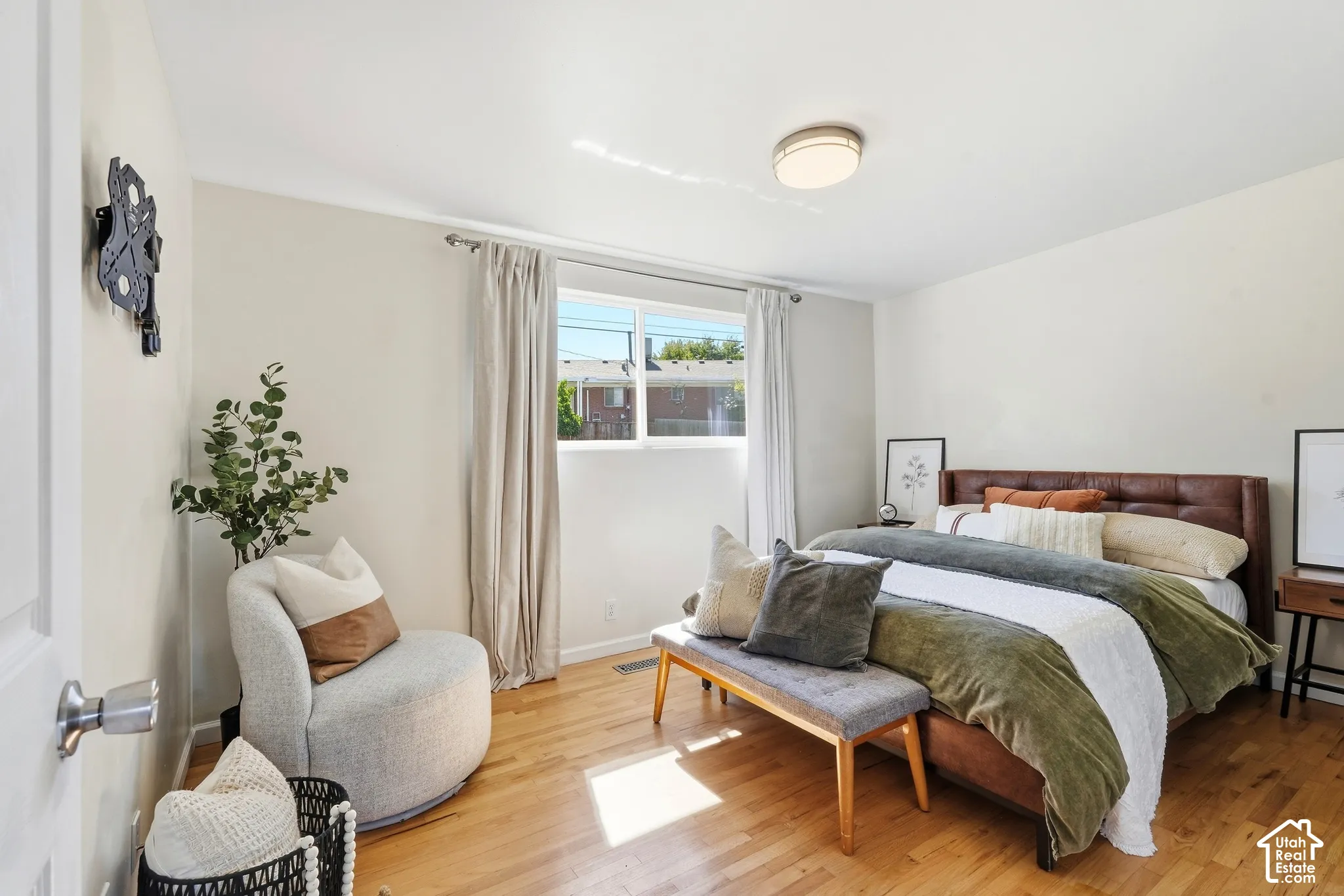 Hardwood flooring, recessed window with curtain rod, ceiling-mounted light fixture, white wall finishes, and a door with a knob