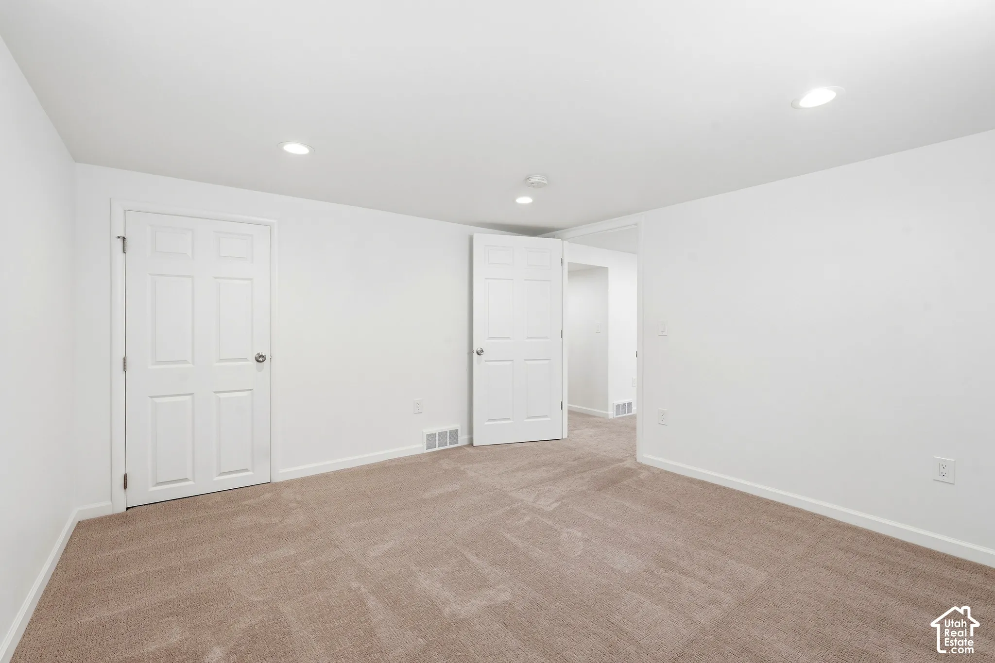 Neutral-toned carpeting, white walls, white trim, recessed ceiling lighting, and white six-panel doors