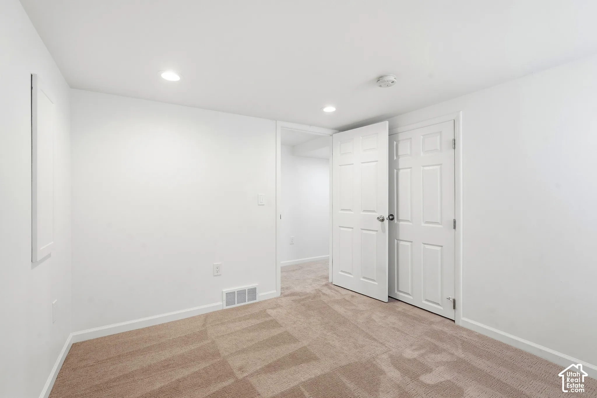 Recessed lighting illuminating neutral wall finishes and patterned carpeting