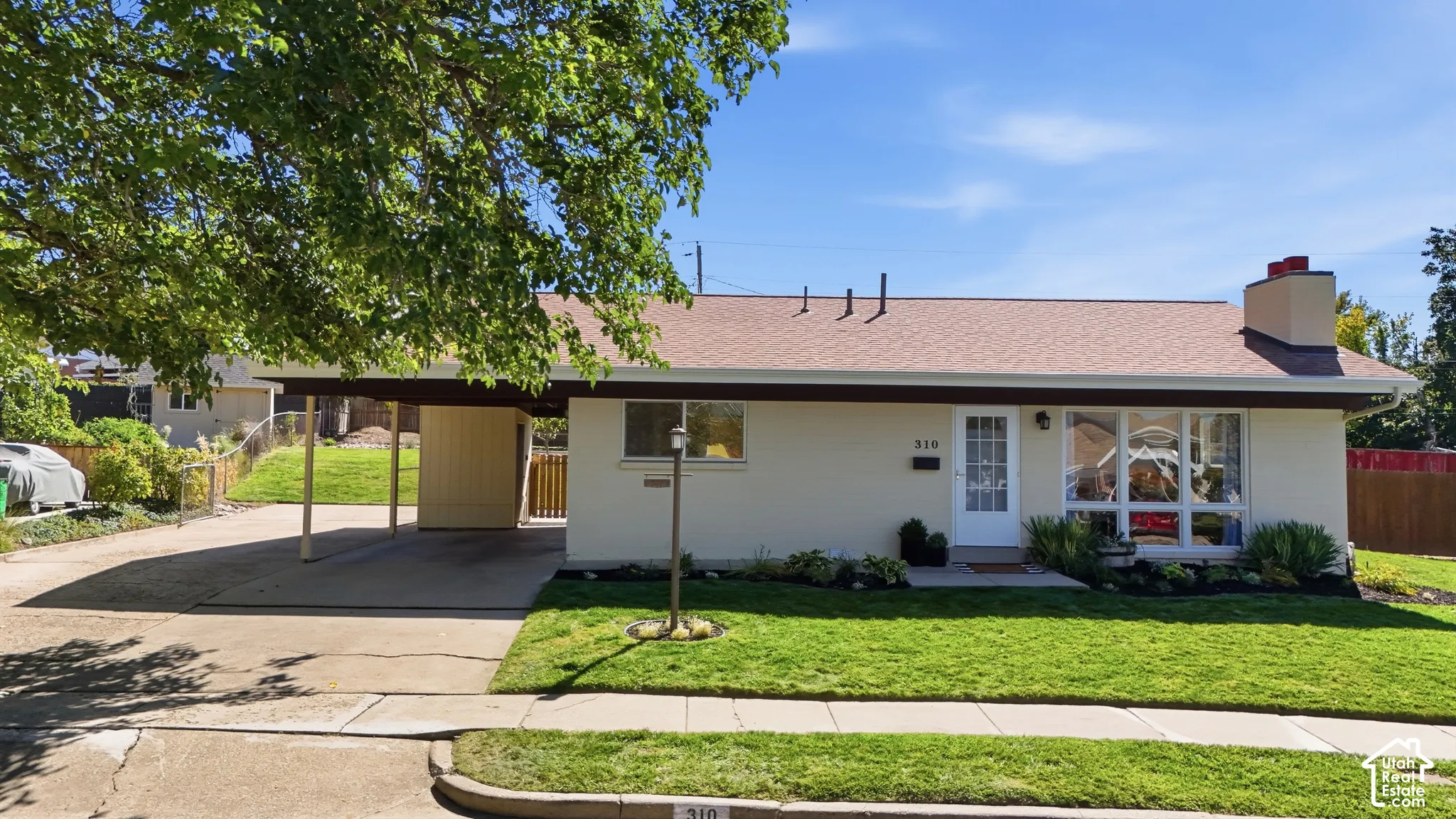 Single-story residence featuring a carport, front lawn, and foundational landscaping