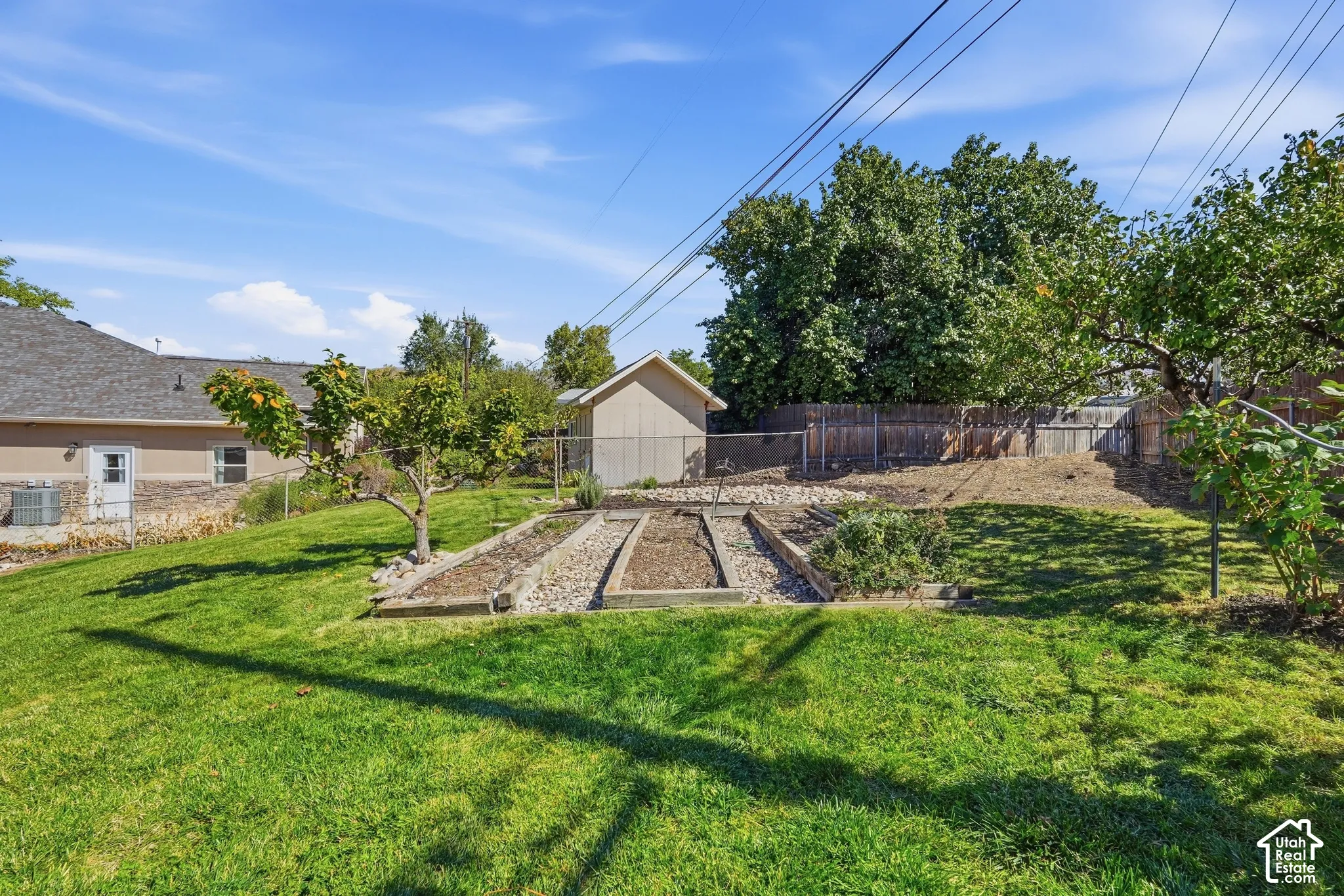 Expansive lawn featuring raised garden beds, mature trees.