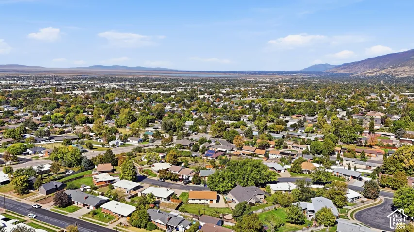 Expansive residential district with mountain backdrop, surrounded by established trees and distant urban elements