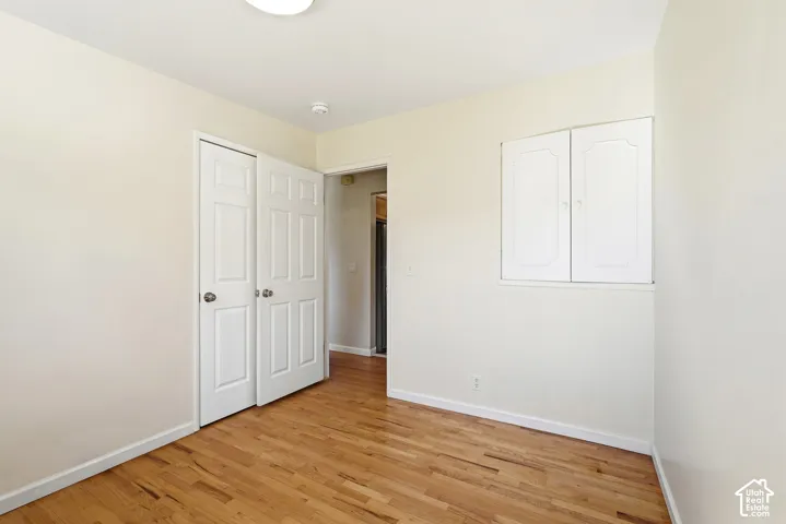 Wood-finish flooring, white bi-fold closet doors, built-in wall cabinet, and a flush-mount ceiling light fixture