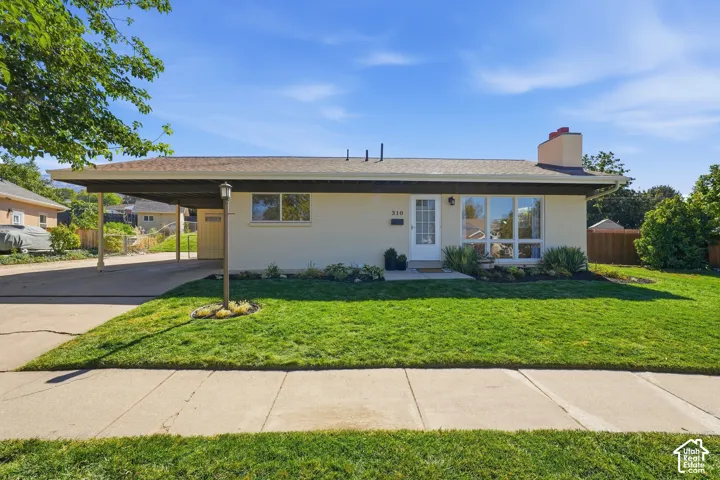 Single-story residence featuring a carport, front lawn, and established landscaping