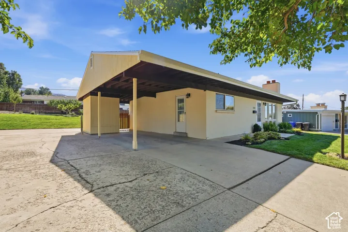 Single-story exterior with a covered carport, manicured front lawn, and landscaped planting beds