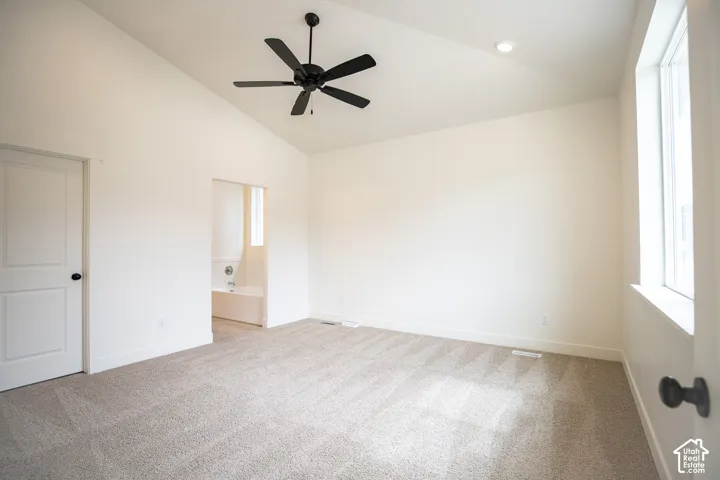 Primary bedroom with vaulted ceiling and ceiling fan.