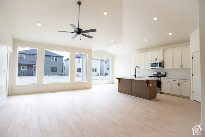 Spacious great room with vaulted ceiling, picture windows and ceiling fan.