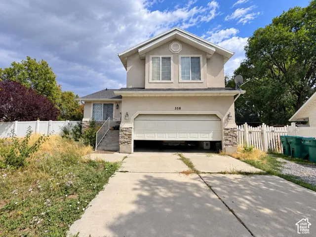 Two-story stucco exterior featuring stone accents, a two-car garage, and a concrete driveway