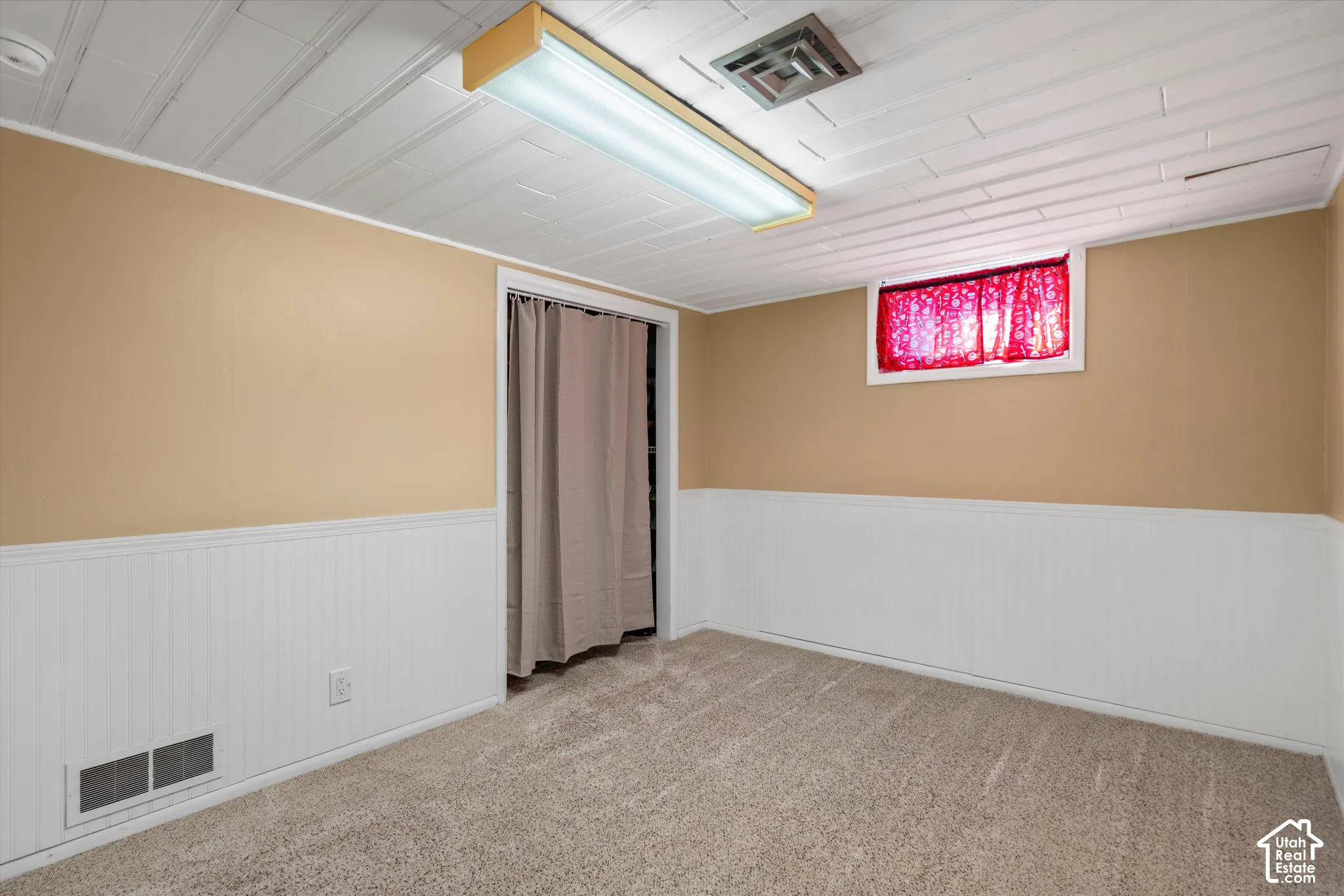 Beige wall paint, white wainscoting, textured carpeting, drop ceiling, and recessed lighting