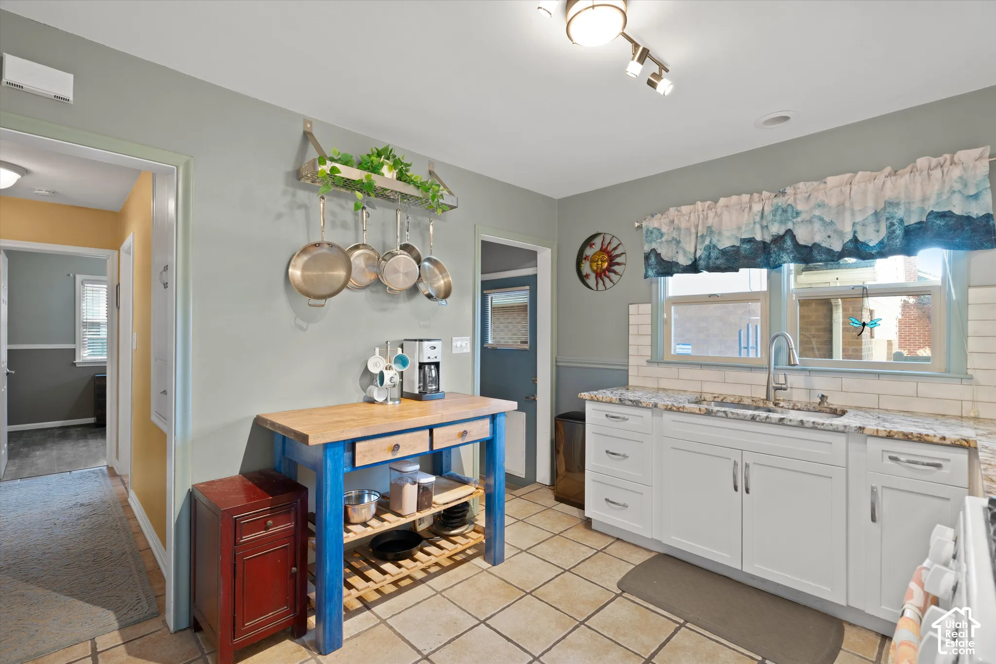 Kitchen featuring white cabinetry, light-toned countertops, a white subway tile backsplash, and tile flooring
