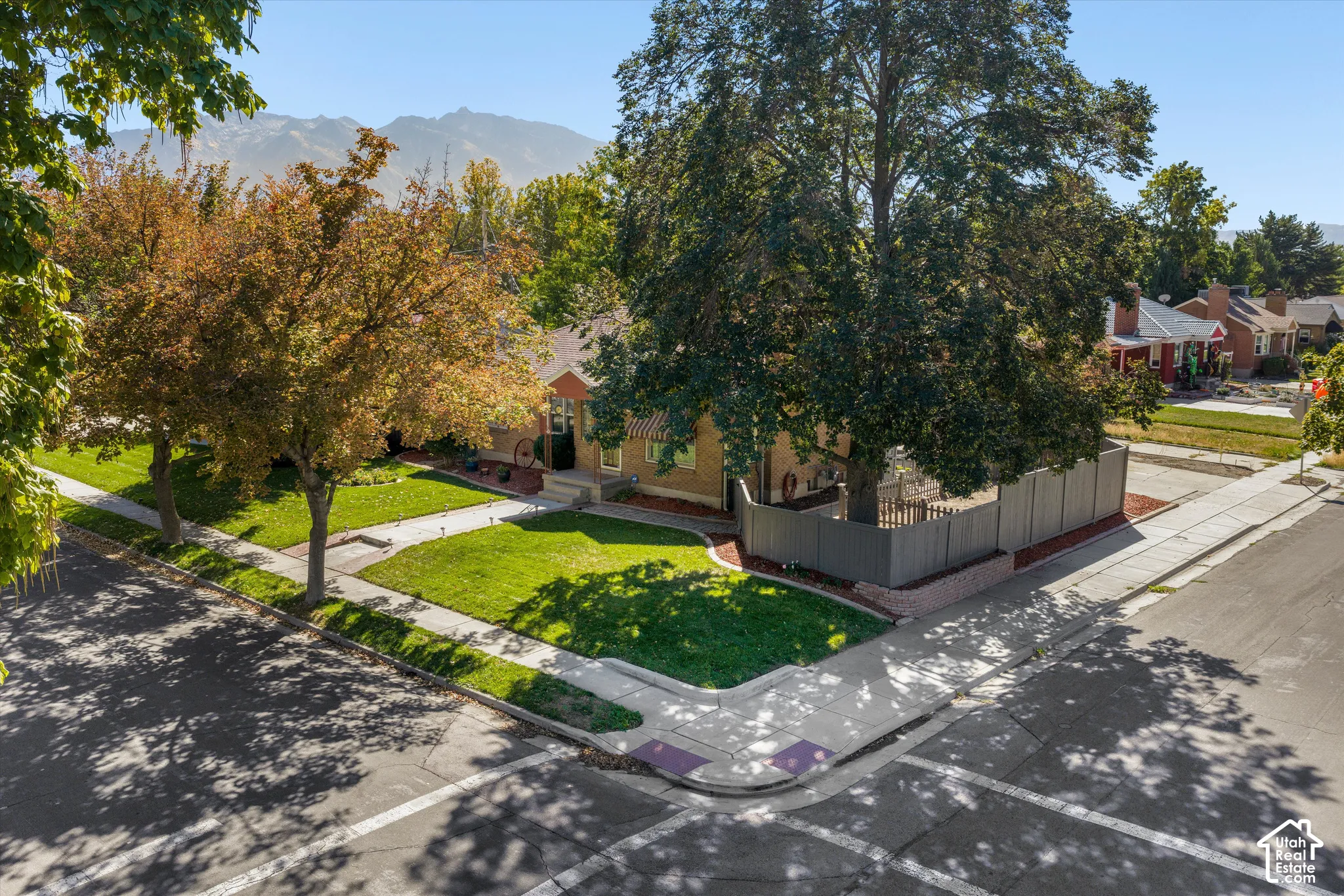 Brick exterior with gabled roofline, mature trees, and a corner lot