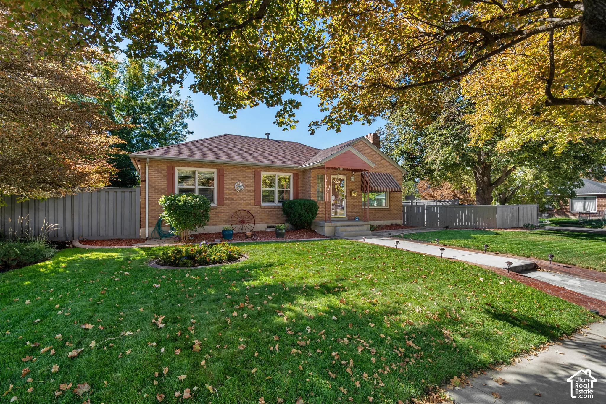 Brick exterior with a shingled roof, featuring front awnings and a paved walkway