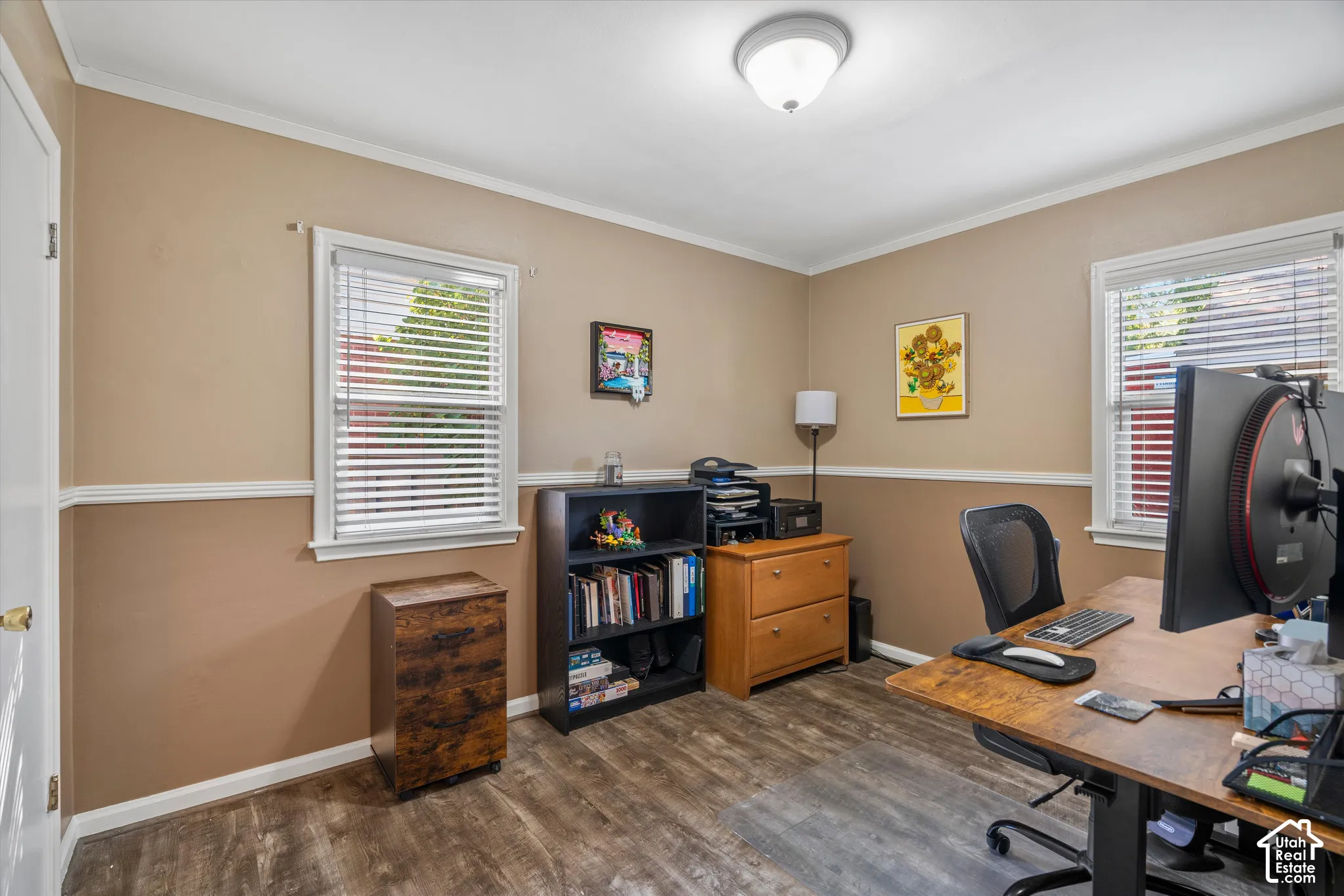 Room featuring two windows with blinds, wood-finish flooring, two-tone wall paint, and crown molding