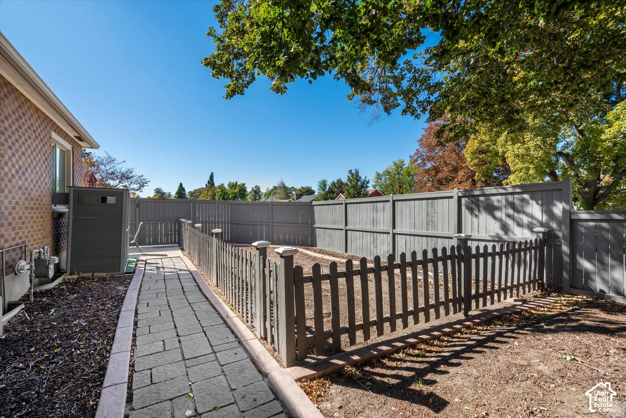 Brick exterior with a paved walkway, wood privacy fence, and an additional low picket fence