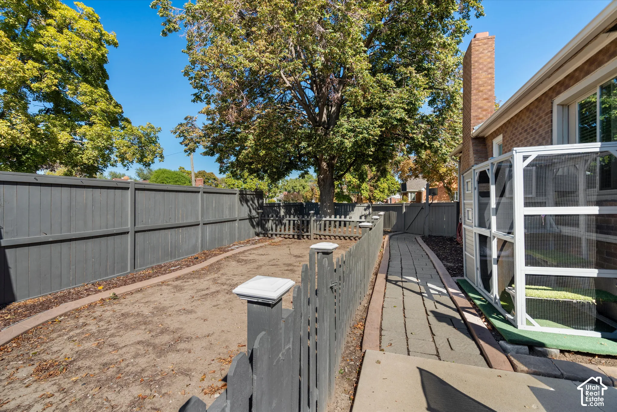 Spacious backyard featuring mature shade trees, newly constructed composite decking with metal railings, metal privacy fencing, and direct access to the home via glass sliding doors