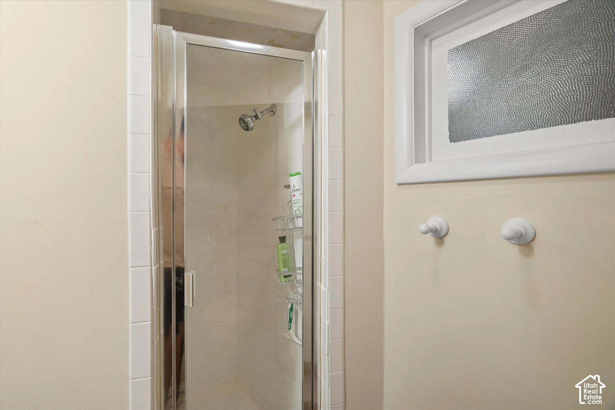 Glass-enclosed shower with a chrome showerhead and white tile surround