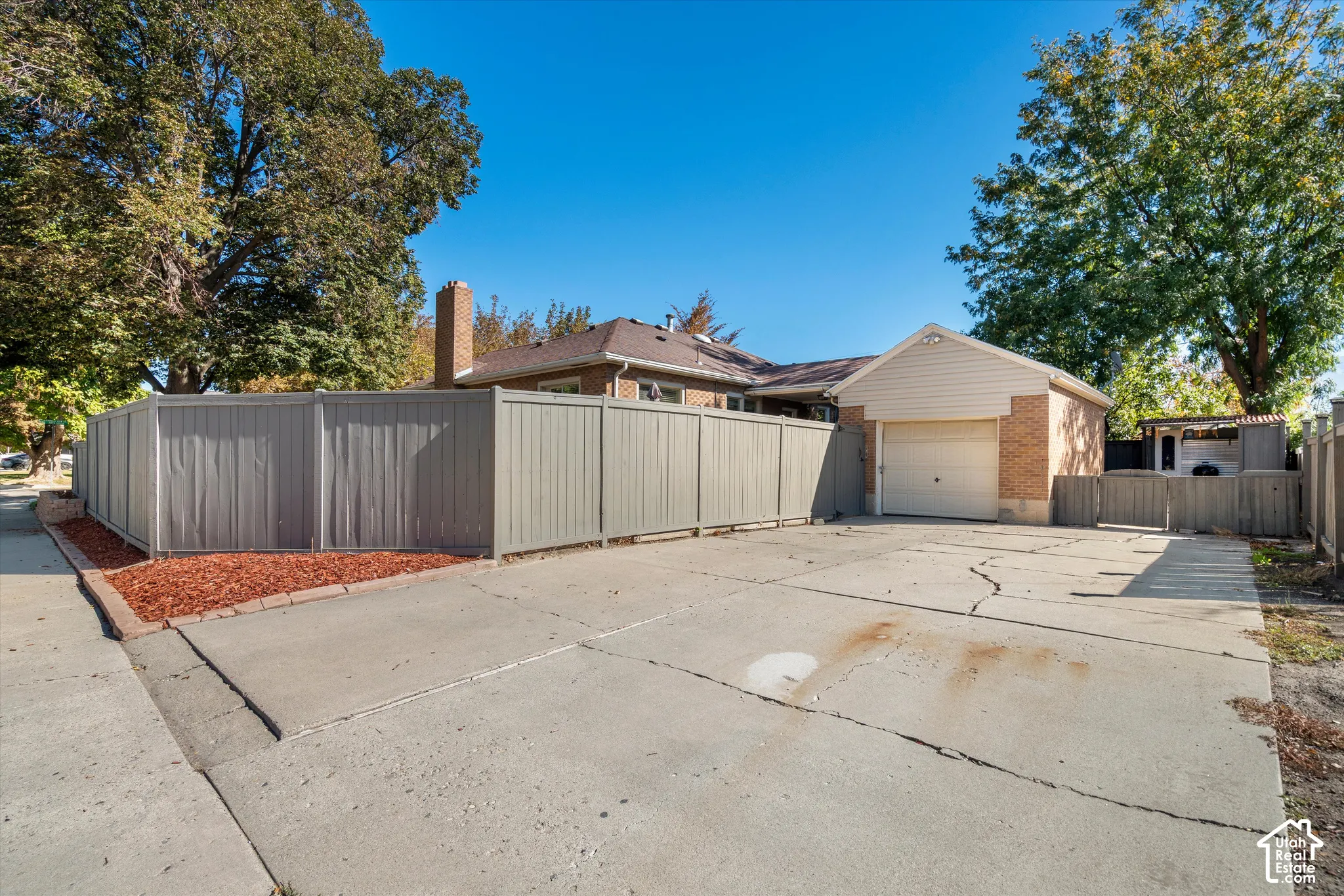 Detached garage with brick facade, concrete driveway, and privacy fencing