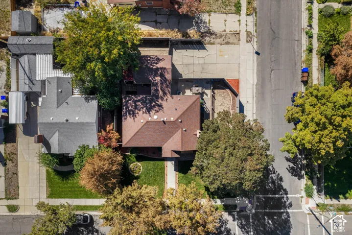 Pitched roofline, mature trees, manicured lawn, paved driveway, and adjacent street