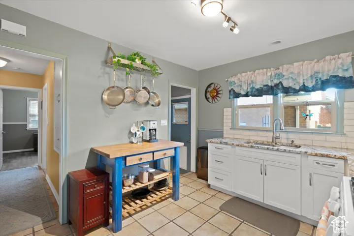 Kitchen featuring white cabinetry, light-toned countertops, a white subway tile backsplash, and tile flooring