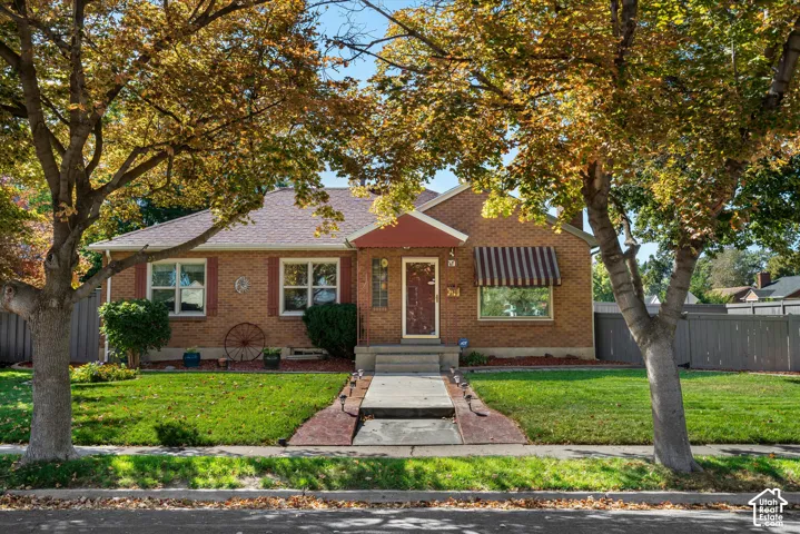 Brick exterior with contrasting window shutters, a covered entry, and a striped window awning