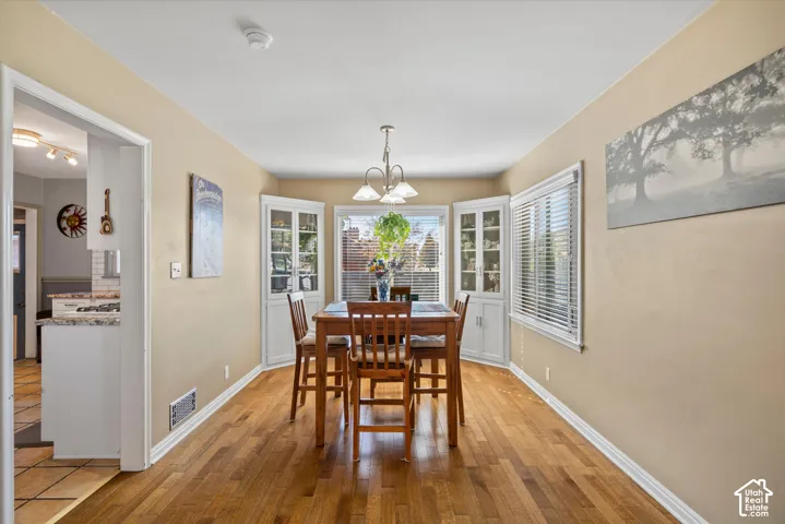 Wood-finish flooring throughout, bay windows with integrated cabinetry, and a chandelier-style ceiling fixture