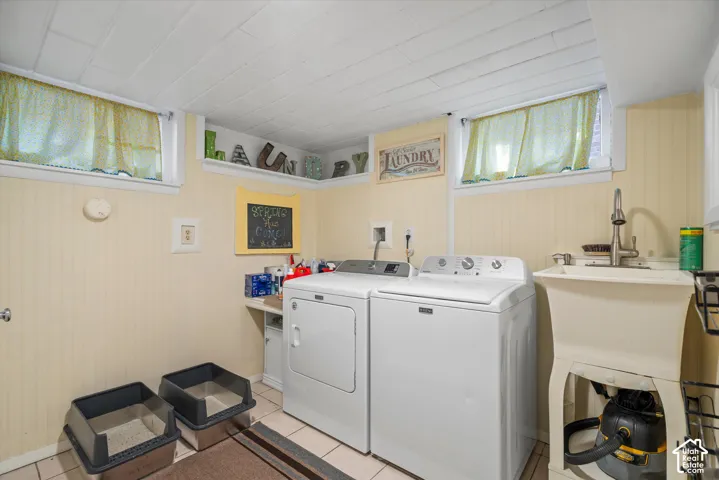 Dedicated laundry area with beadboard paneling, tiled flooring, and a utility sink with a high-arc faucet