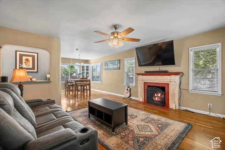 Hardwood flooring throughout, a ceiling fan with integrated lighting, and a fireplace with a decorative mantel