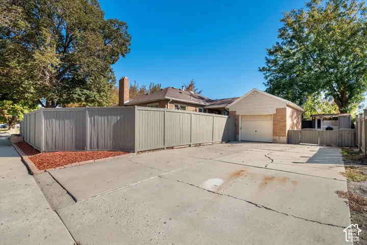 Detached garage with brick facade, concrete driveway, and privacy fencing