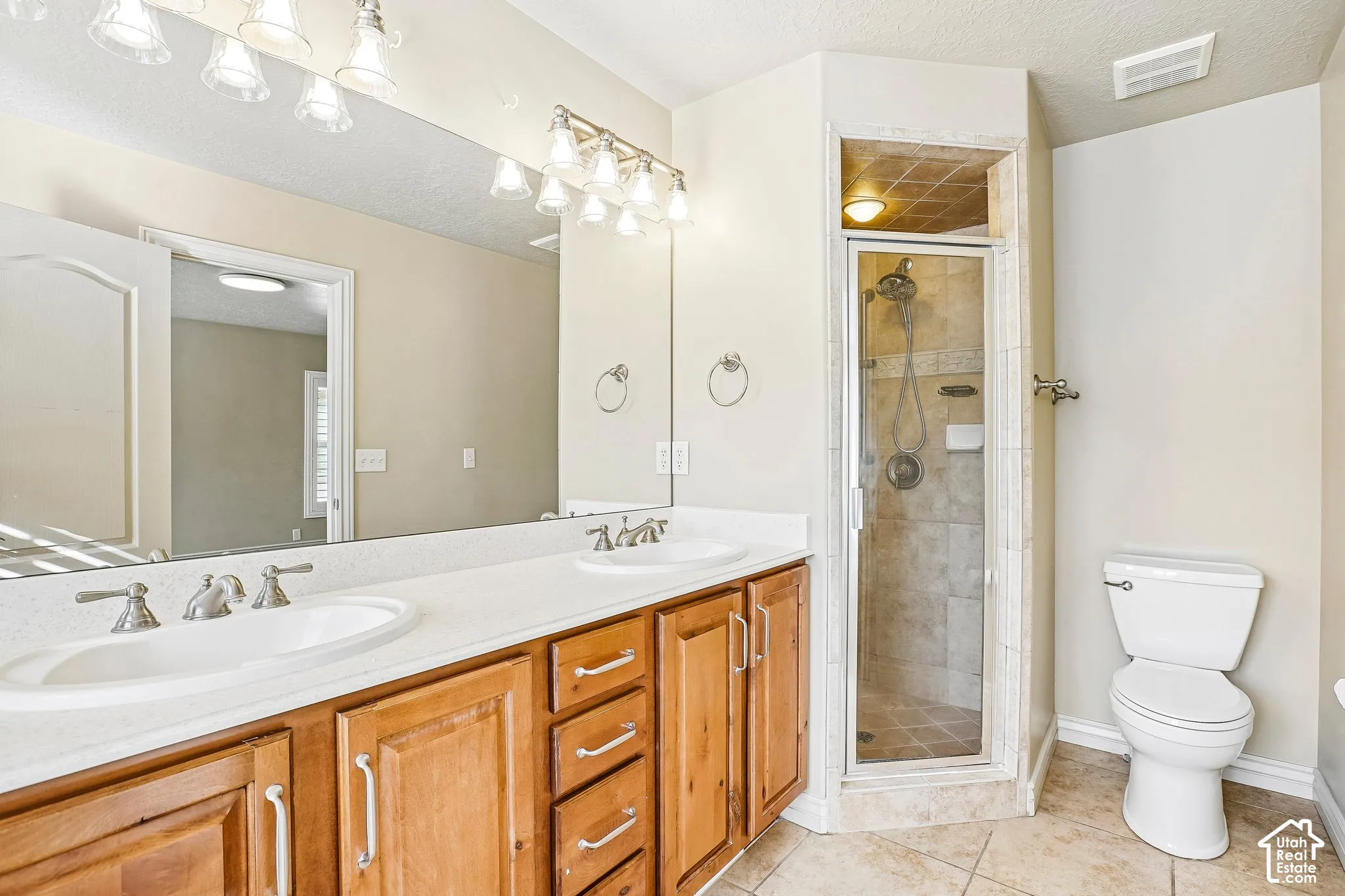 Dual vanity with undermount sinks, wood-finish cabinetry, and a full-width mirror