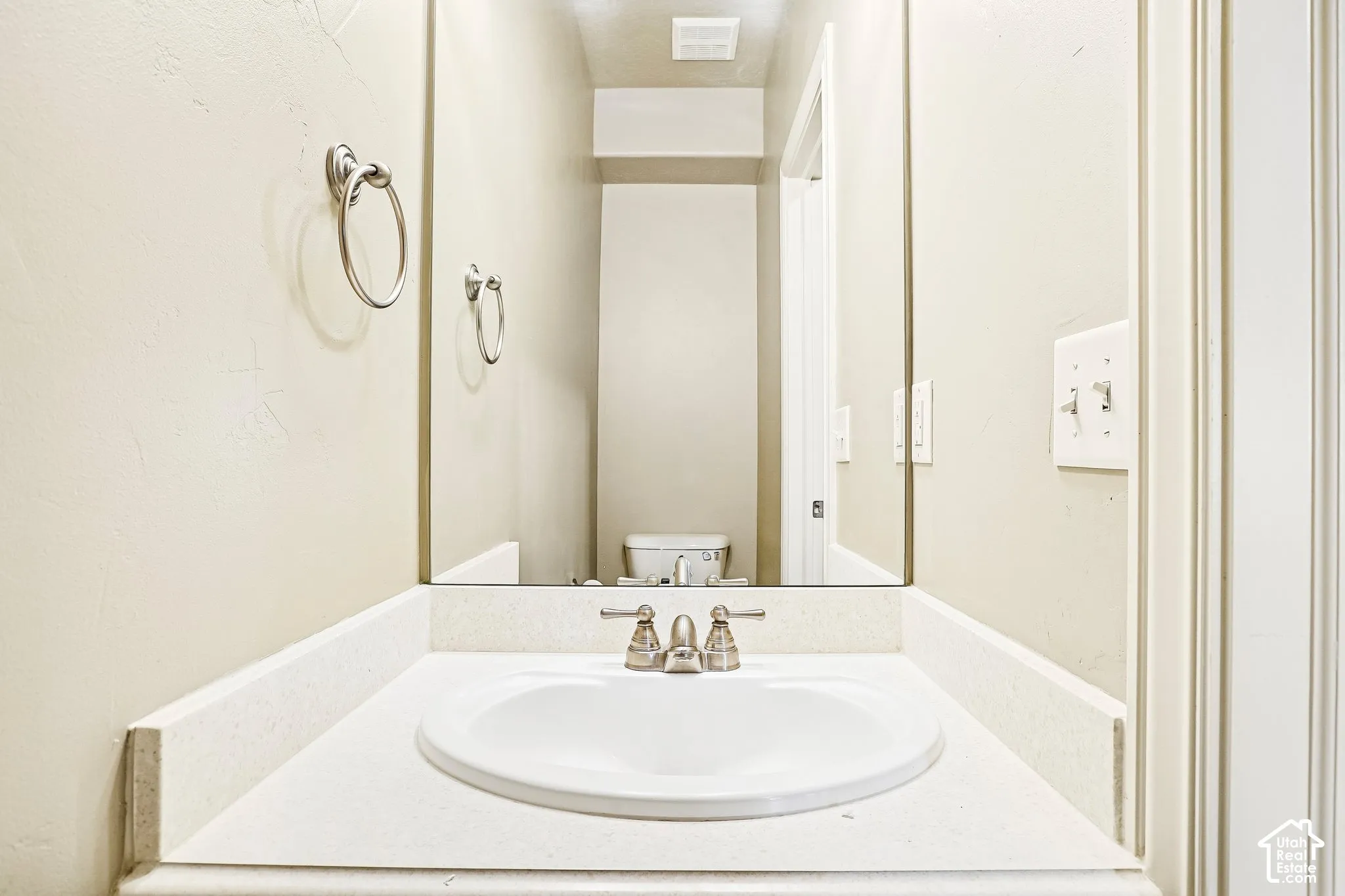 White countertop with an integrated oval sink and brushed nickel faucet