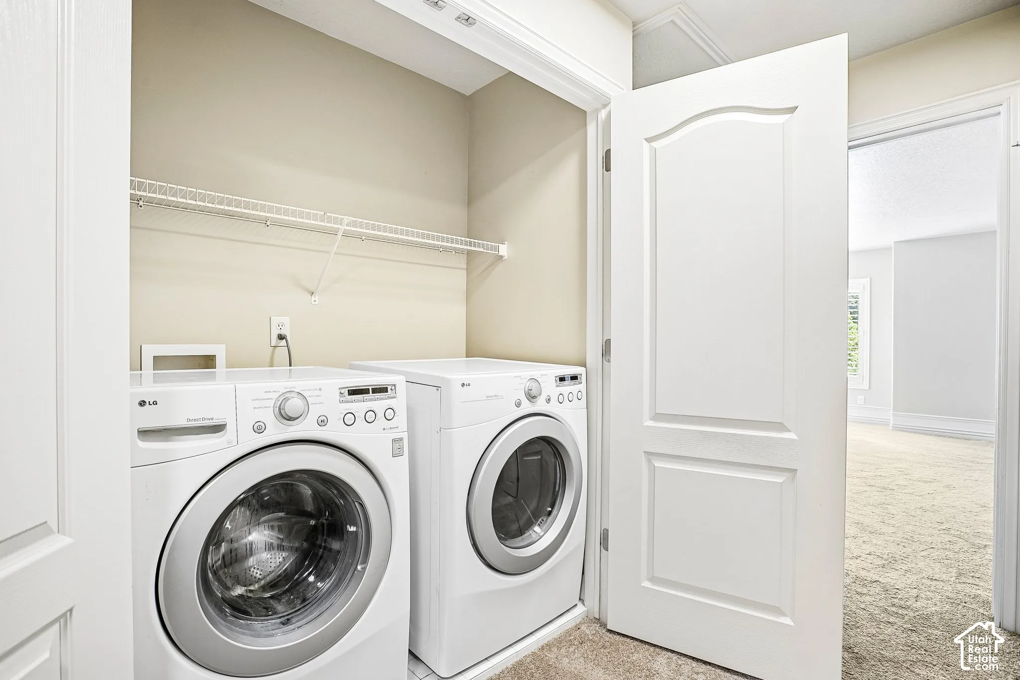 Dedicated laundry closet featuring a wire storage shelf and front-loading appliances
