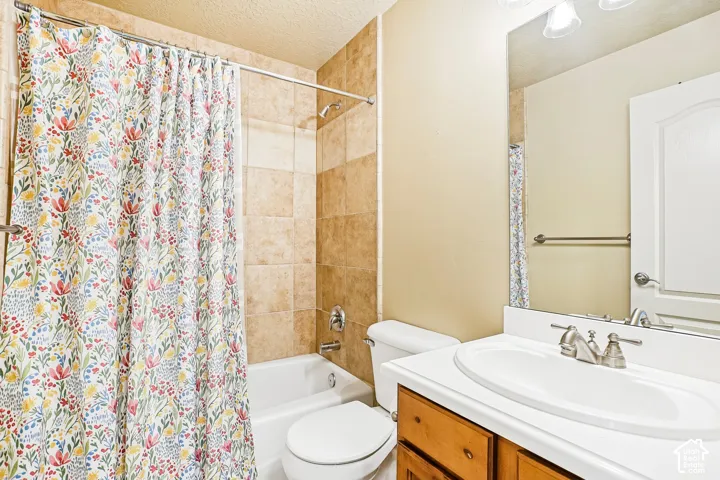 Tub and shower combination with tile surround, wood-finish vanity with countertop, and an integrated sink