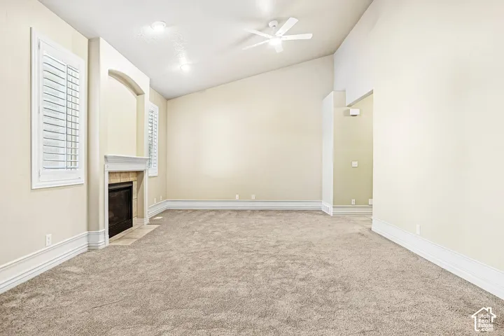 Vaulted ceiling with a ceiling fan, recessed lighting, fireplace with a mantel, plantation shutters, and carpet flooring