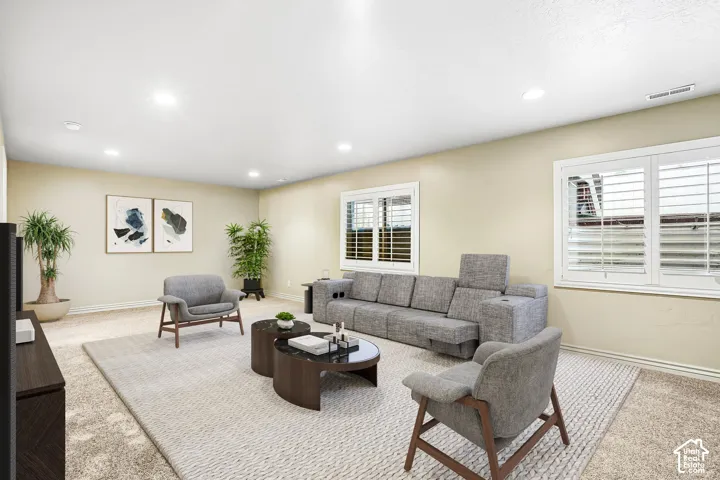 Recessed lighting illuminates the space, featuring carpeting and multiple windows with plantation shutters