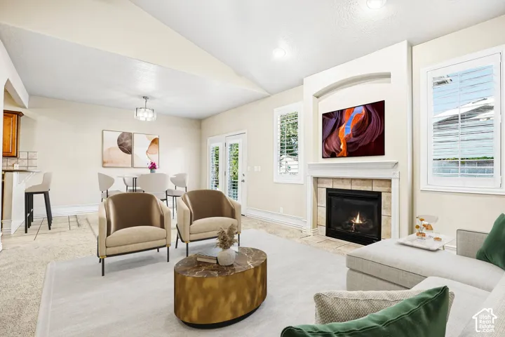 Living area featuring a vaulted ceiling and a fireplace with a tile surround and mantel