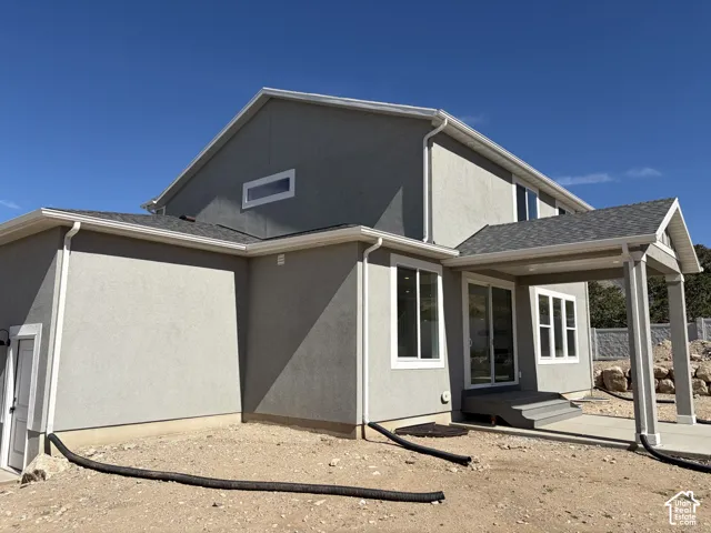 Exterior featuring a covered patio, multiple large windows, and a basement access door