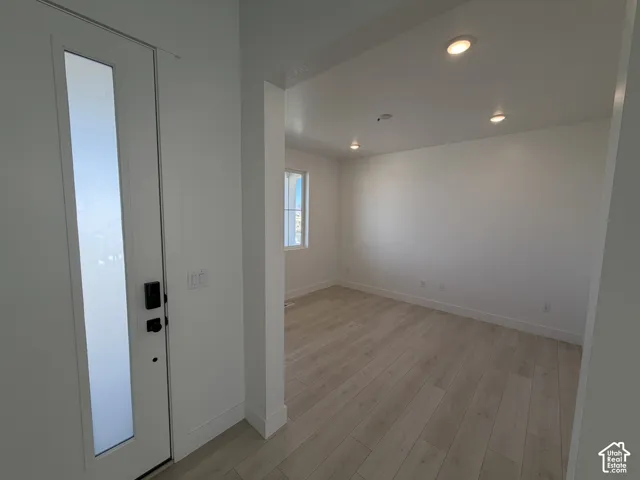 Entry with a full-lite door and dark hardware, opening to a room with wood-finish flooring, recessed lighting, and a window