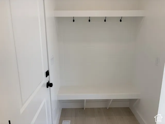 Built-in bench with storage, shiplap-style wall paneling, overhead shelf, and coat hooks