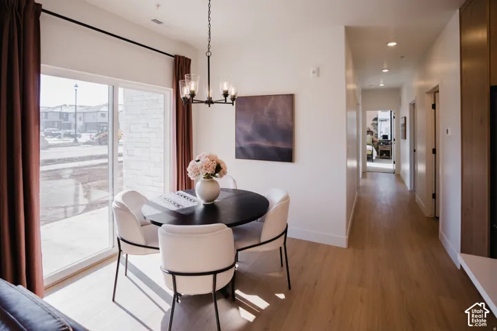 Dining area featuring wood-finish flooring, a contemporary chandelier, and a sliding glass door