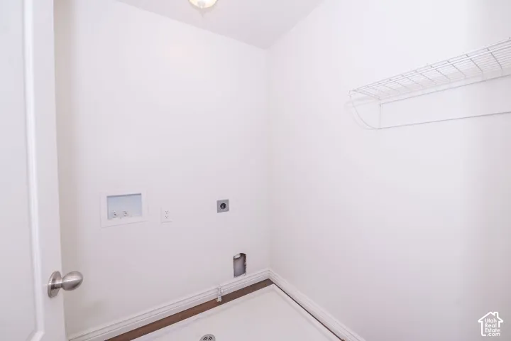Laundry area featuring a wire shelf, overhead lighting, and utility hookups
