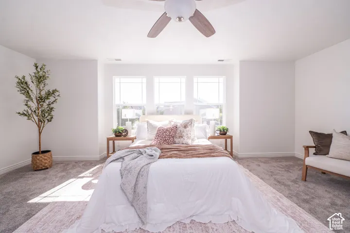 Bright room with three windows, a ceiling fan, and carpeted flooring