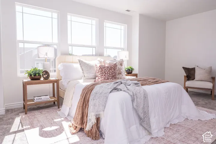 Recessed lighting, three large windows, textured carpeting, and white painted walls