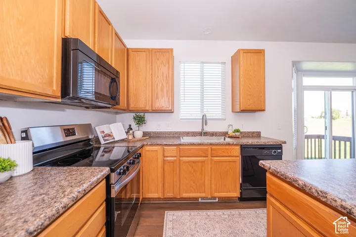 Wood-finish cabinetry, stone-finish countertops, stainless steel range, and a built-in microwave