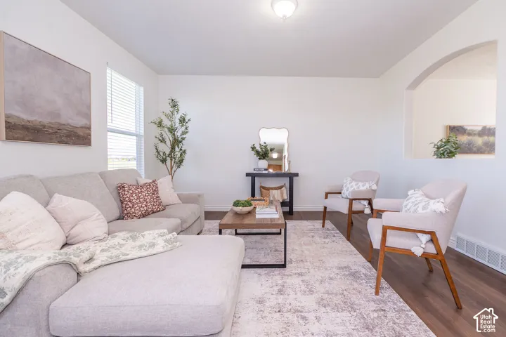 Spacious room featuring wood-finish flooring, a rectangular window with blinds, and a built-in arched alcove