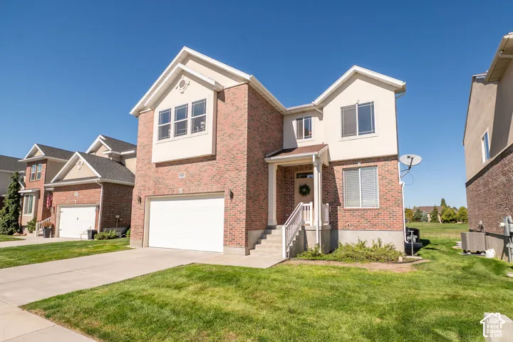 Brick and stucco exterior with multiple gables, an attached garage, and a covered entry